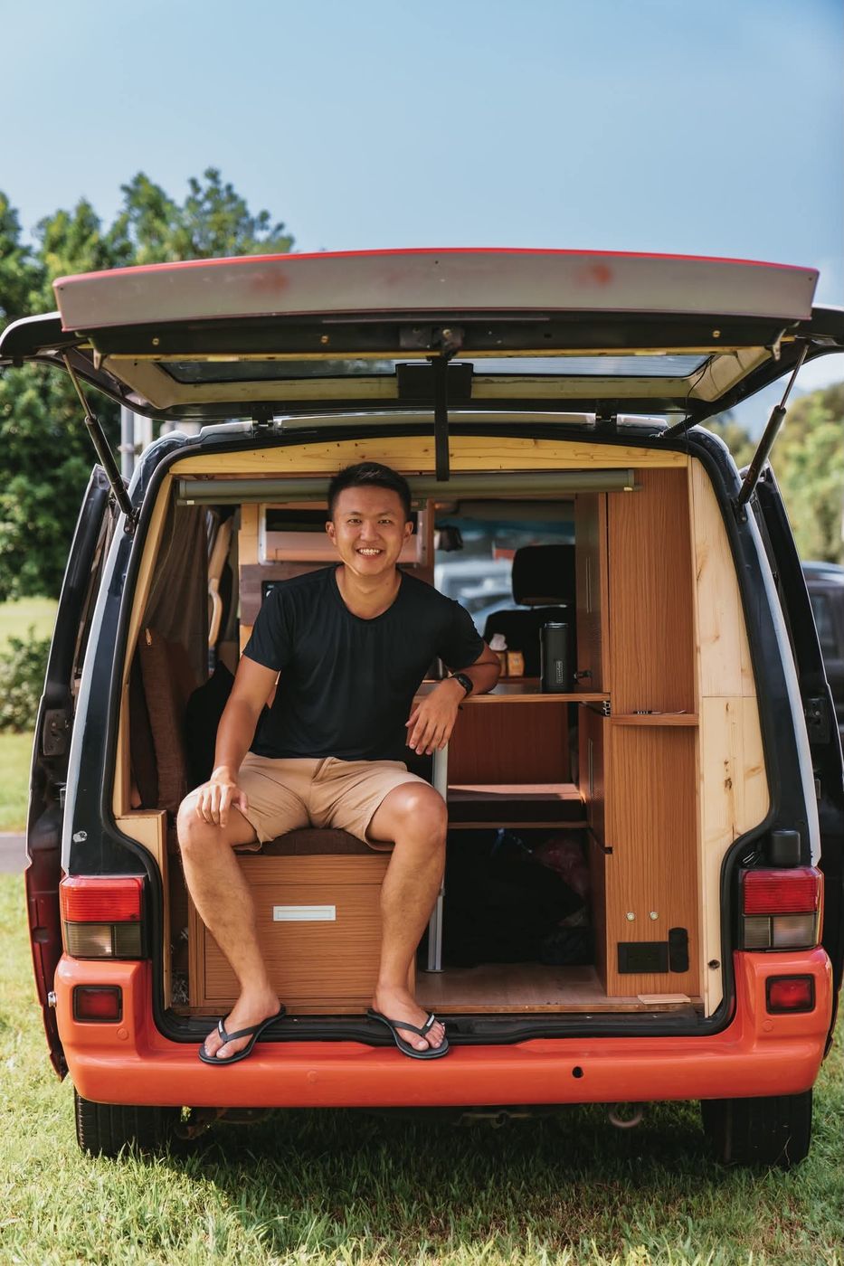 Andrew sitting in the open back of his converted van, a plywood-fitted mobile office.